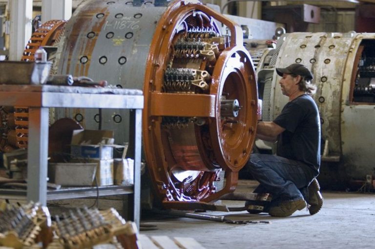Technician working on a disassembled traction motor in a railway maintenance workshop