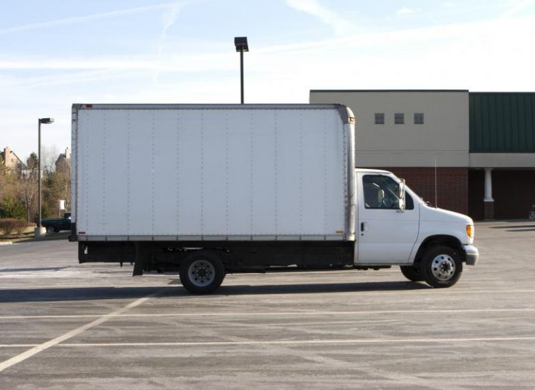 A person loading boxes into a moving truck at a rental location.