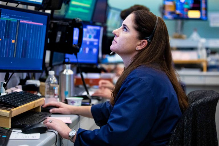 Traders watching and analyzing stock market data on multiple computer screens in office